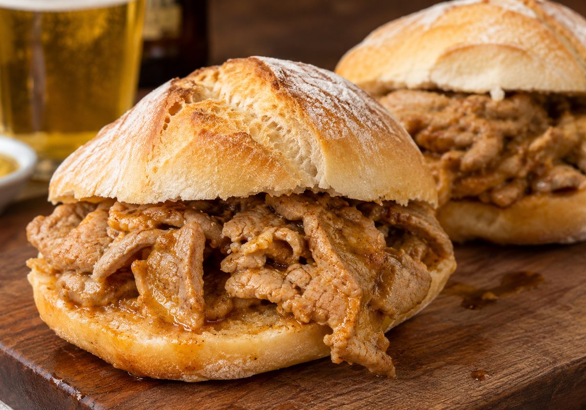 Bifanas no pão, com carne de porco grelhada, sobre mesa de madeira